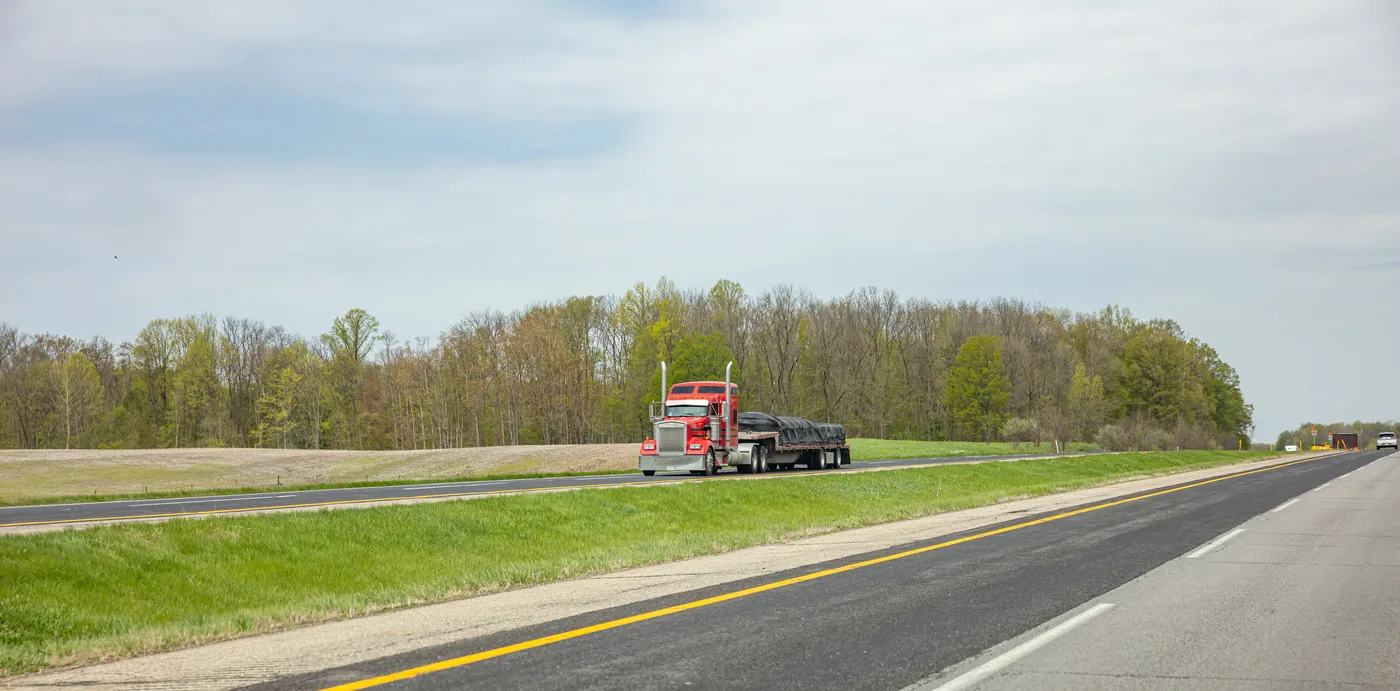 Semi truck with a flatbed trailer on a divided highway
